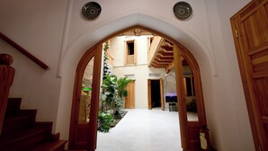 An arched hallway leading to a room with a view of a balcony and a door with a number. - AIST HOTEL (Bukhara)