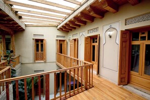 A wooden balcony with a glass floor, wooden railings, and a traditional design. - AIST HOTEL (Bukhara)