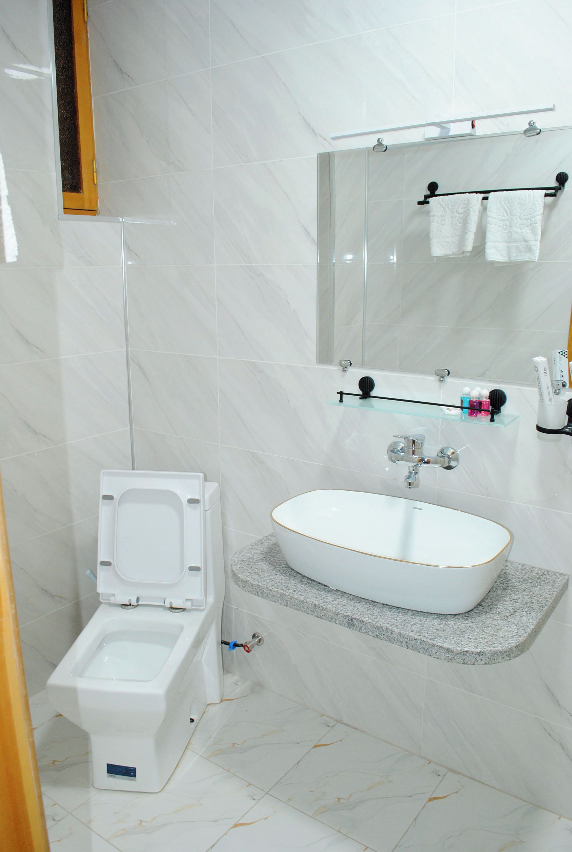 A bathroom with a toilet, a sink, and a mirror.