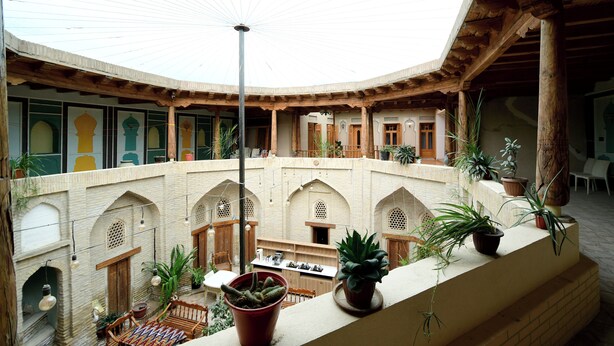A courtyard with a high ceiling, arches, and potted plants. - AIST HOTEL (Bukhara)