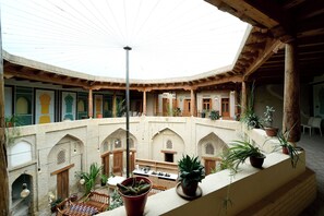 Une cour dotée d’un haut plafond, d’arcades et de plantes en pot.