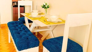 Un espace repas avec une table dressée pour quatre personnes, des bancs, une machine à café et des œuvres d’art murales.