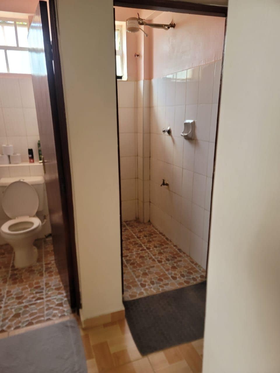 A bathroom with a toilet, a shower, and a tiled floor.