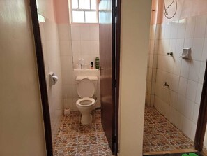 Een compacte badkamer met toilet, douchecabine en betegelde vloer.