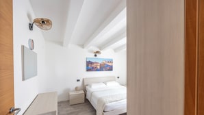 Une chambre à coucher comprenant un lit, des tables de chevet, une commode, une lampe fixée au mur et un tableau.