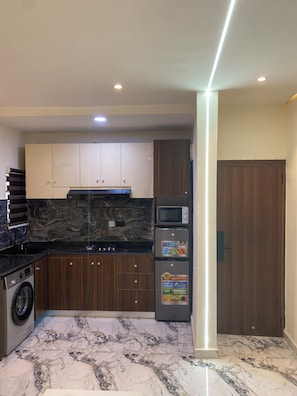 A modern kitchen with marble flooring, built-in appliances, and wooden cabinets. - Luxury & Modern Self Check-In Apts near Airport M01a (Lagos)