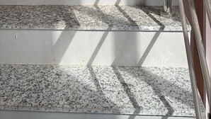 Una escalera de granito con barandilla metálica que lleva a una habitación con extintor en la pared.