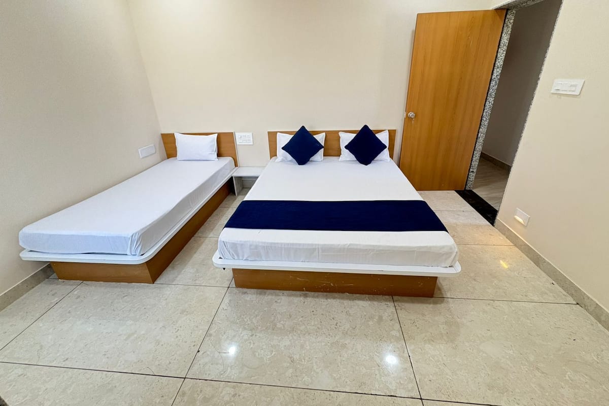 A hotel room with two single beds and a larger bed.
