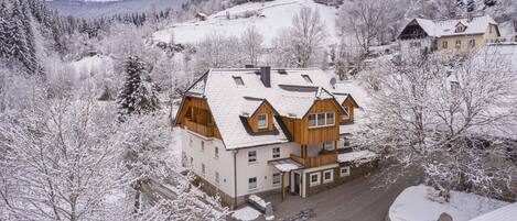Un edificio de varios pisos con base de piedra, estructura de madera y techo cubierto de nieve.