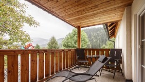 A covered balcony with wooden railings, two lounge chairs, and a table. - Apartment in St. Georgen Near Kreischbergbahn (Sankt Georgen am Kreischberg)