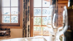 Una stanza con un'ampia finestra, travi in legno e vista sulle montagne innevate.