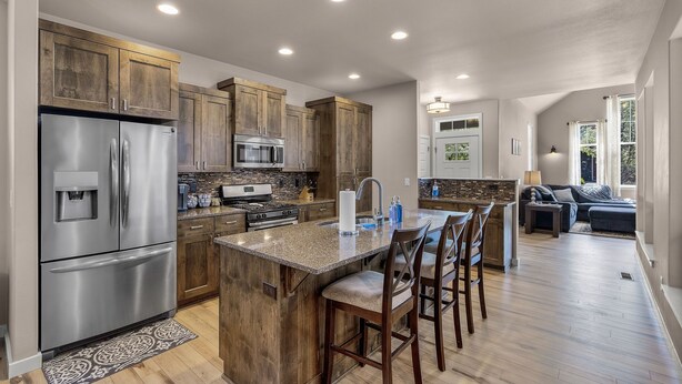 A modern kitchen with stainless steel appliances, wooden cabinets, and a central island with bar stools.