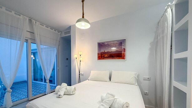 Ein Hotelzimmer mit einem großen Bett, einem Bild an der Wand und Blick ins Freie durch das Fenster.