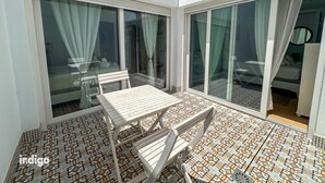 Ein Zimmer mit Fliesenboden, einem Tisch und Stühlen sowie großen Schiebeglastüren.