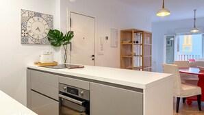 Eine moderne Küche mit Backofen, weißer Arbeitsplatte und einer dekorativen Uhr.