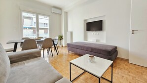 Una sala de estar moderna con un sofá, una mesa de centro y un televisor montado en la pared.