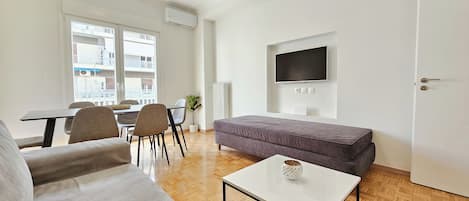 A modern living room with a sofa, a coffee table, and a TV mounted on the wall.
