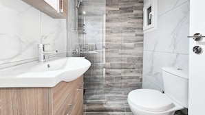 Un baño moderno con tocador de mármol, cabina de ducha y un inodoro.