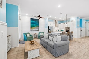 Una sala moderna con un sofá gris, sillones color turquesa y una mesa de centro de madera.