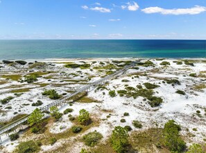 Un paisaje costero con un muelle de madera que lleva a la playa.