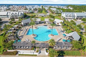 Un resort con piscina central rodeada de tumbonas y palmeras.