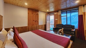 Ein Zimmer mit Holzwänden, einem Bett, einer Couch und einem Fenster mit Blick auf Berge.