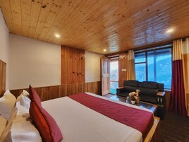 Habitación con paneles de madera, una cama, un sofá y una ventana con vistas a la montaña.