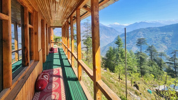 Ein Holzbodenkorridor mit grünem Belag führt zu einem Balkon mit Bergblick.