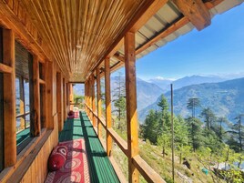 Un pasillo de madera con piso verde que conduce a un balcón con vistas a la montaña.
