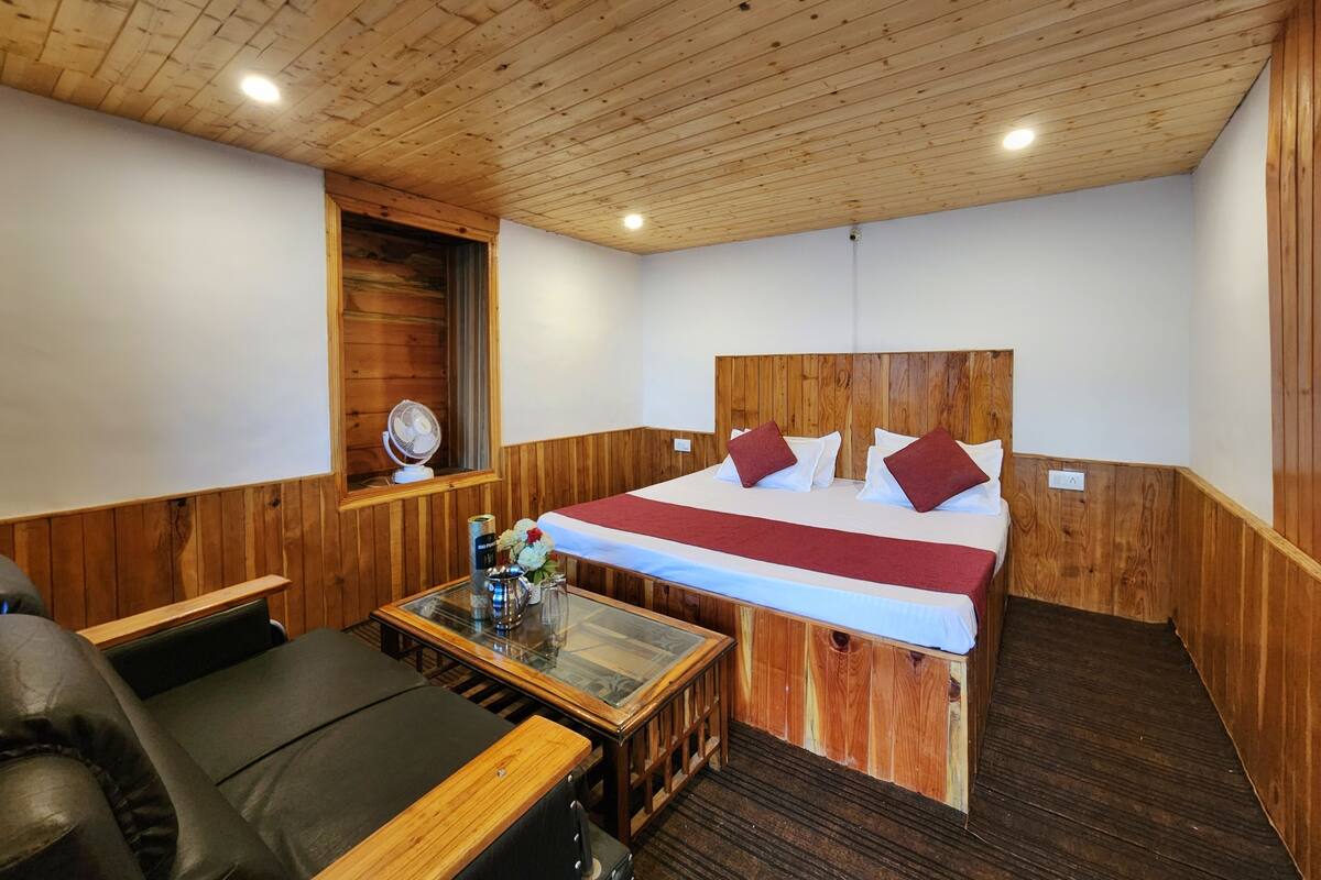 A wooden-paneled room with a bed, a table, and a chair.