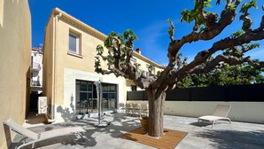 Une cour avec un arbre, des sièges en plein air et un bâtiment doté de grandes fenêtres.
