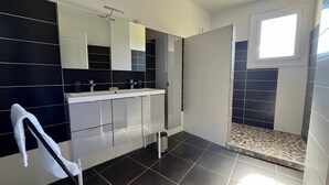 Une salle de bain moderne avec un grand miroir, un double vasque et un espace douche.