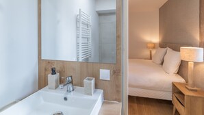 Un baño moderno con un espejo grande, un lavamanos blanco y un tocador de madera.