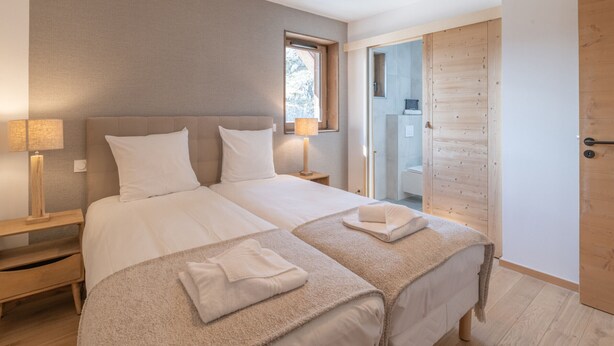 Un dormitorio moderno con una cama grande, lámparas de noche, una ventana y una puerta de madera.