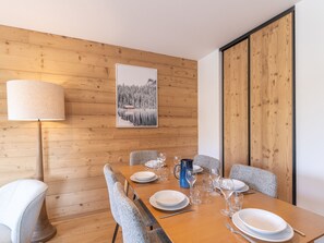 A dining area with a wooden table set for four, chairs, a lamp, and a framed picture on the wall.