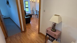 A hallway with wooden flooring leading to a dining area with a table and chairs.