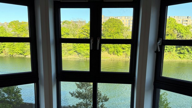 A corner window with a view of a lake and trees.