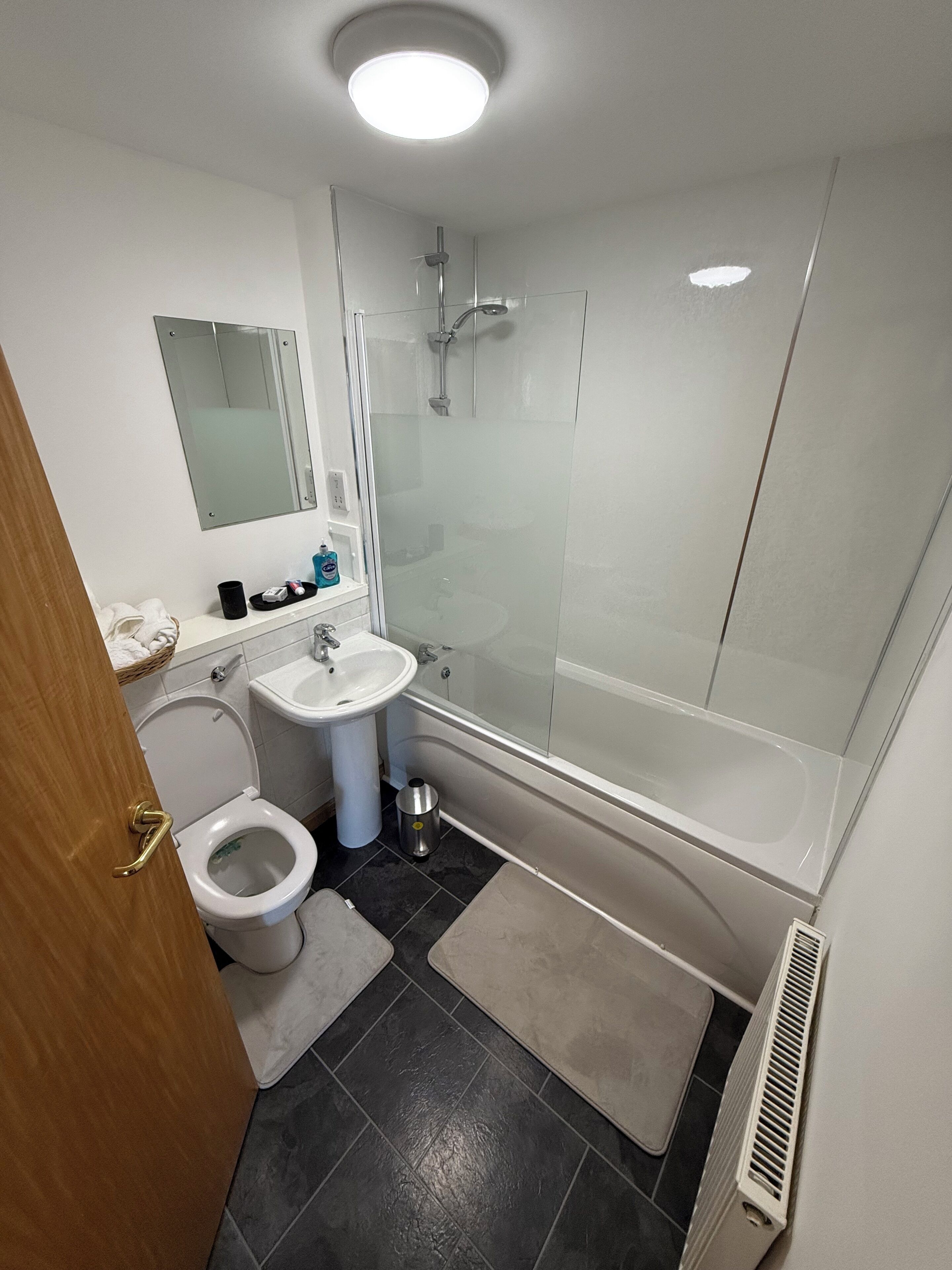 A modern bathroom with a glass-enclosed shower, a white sink, and a toilet.