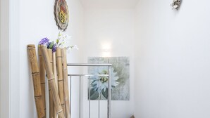 Eine Treppe mit Holzboden und Metallgeländer, die zu einem Raum mit einem großen floralen Gemälde an der Wand führt.