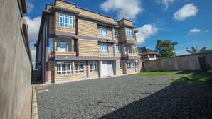 A multi-story building with a stone facade, large windows, and a gravel driveway. - Hallel Guest House (Nakuru)