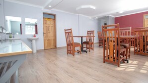 A spacious room with a wooden dining table and chairs, a sink, and a mirror. - Hallel Guest House (Nakuru)