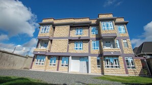 A multi-story building with a stone facade, multiple windows, and a gated entrance. - Hallel Guest House (Nakuru)