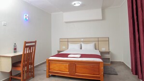 A hotel room with a wooden bed, a desk, and a chair. - Hallel Guest House (Nakuru)