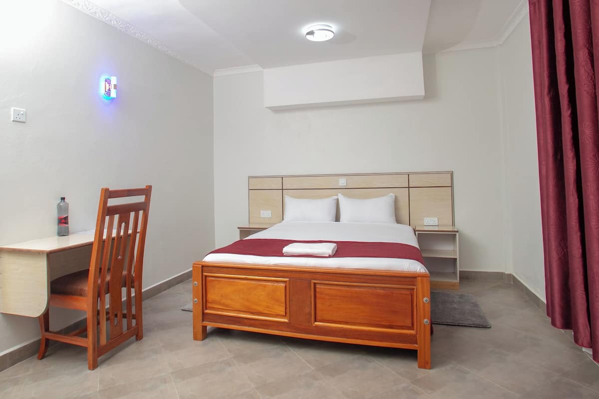 A hotel room with a wooden bed, a desk, and a chair.