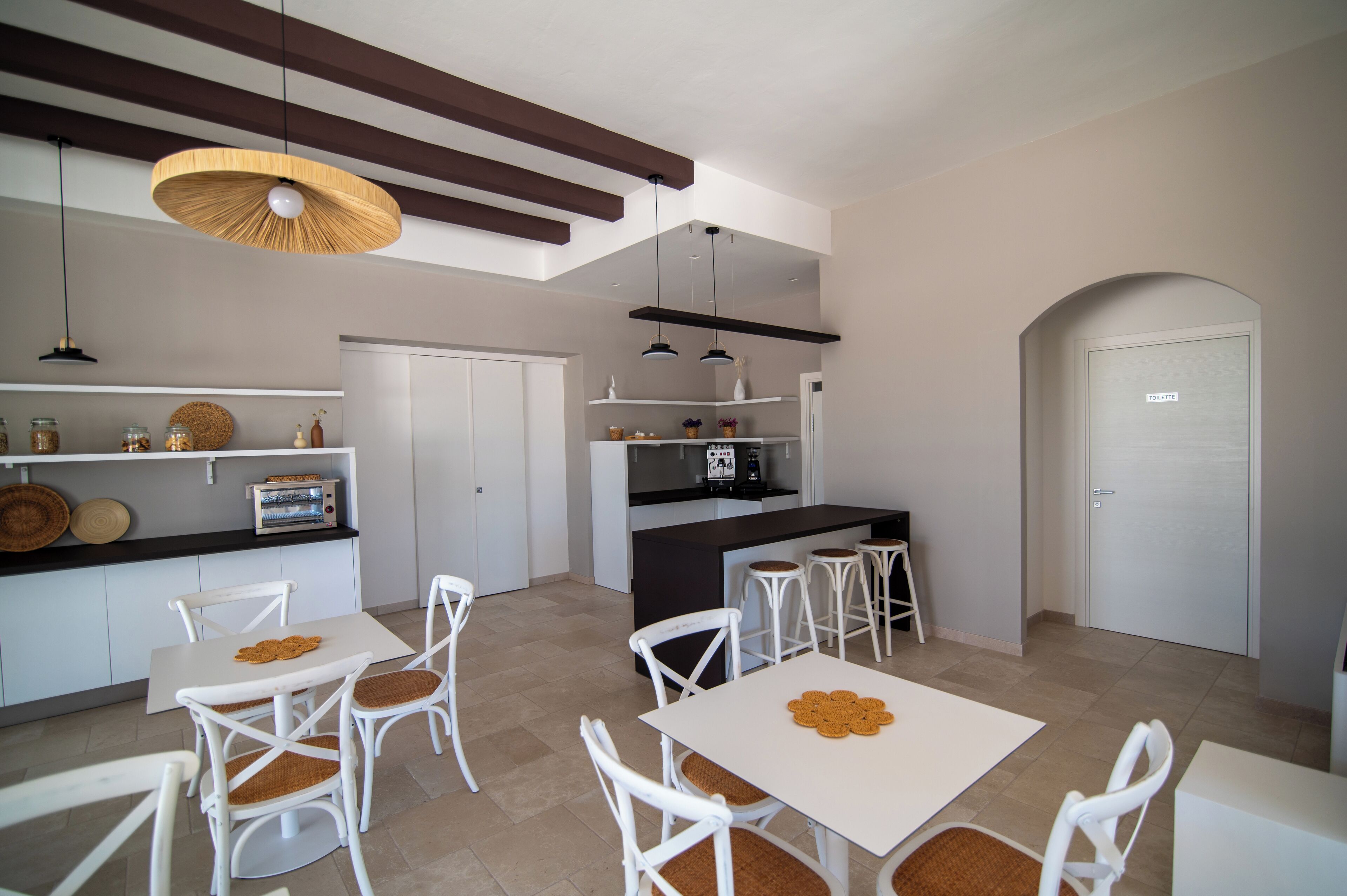 Una cocina moderna con armarios blancos, una isla central y un comedor con sillas blancas.
