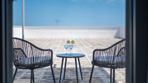 A terrace with two chairs and a table, a clear sky, and a distant view of a building. - Il Casale nel Parco (Ostuni)