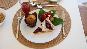 A plate with a slice of cake, strawberries, and a muffin on a placemat.