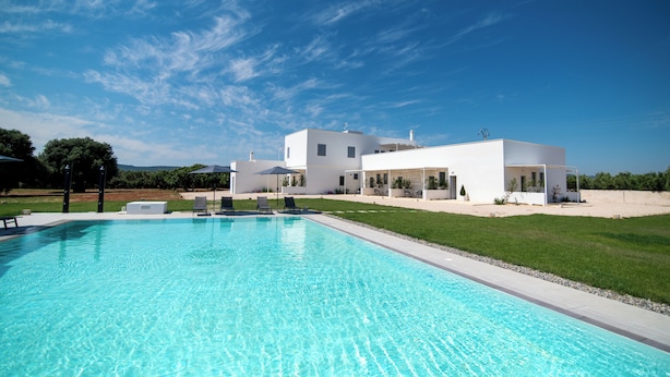 A modern white house with a swimming pool, surrounded by a well-maintained lawn and a clear blue sky. - Il Casale nel Parco (Ostuni)
