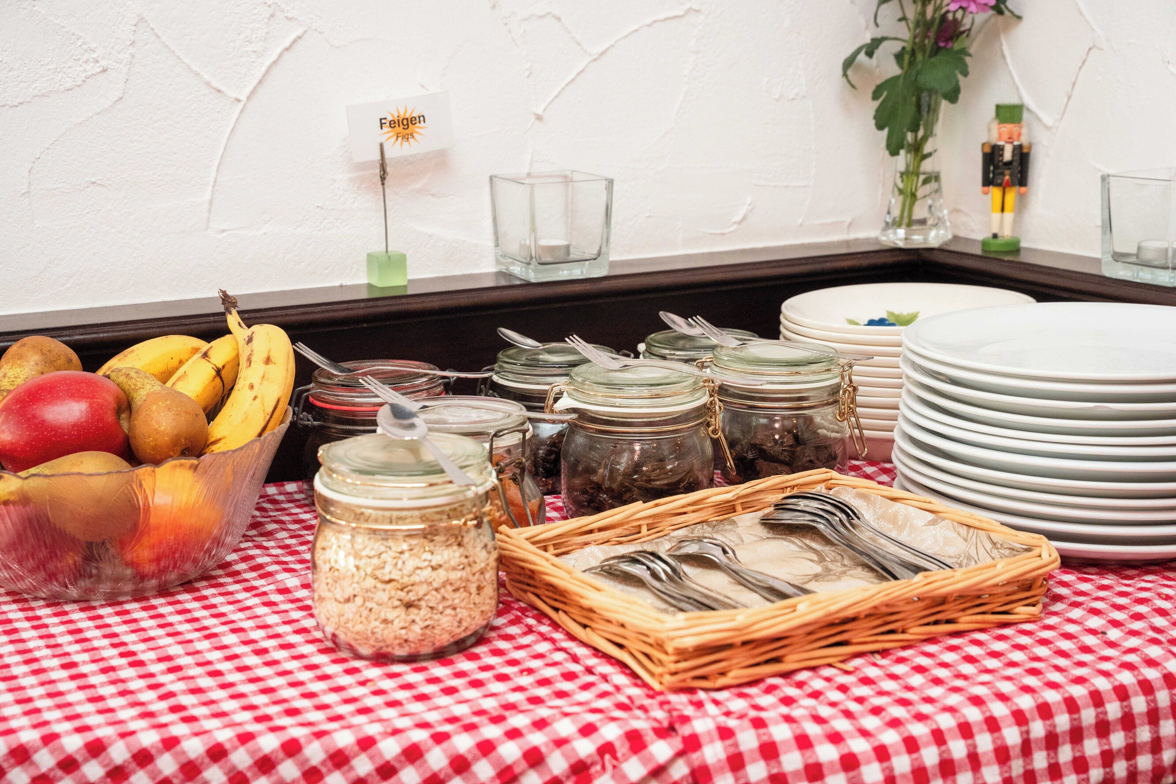 A breakfast buffet setup with a variety of food items and utensils on a checkered tablecloth.