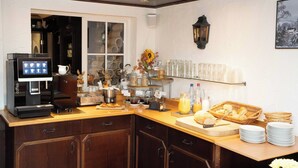 Una barra de desayuno con una máquina de café, pasteles y diversas opciones para el desayuno.